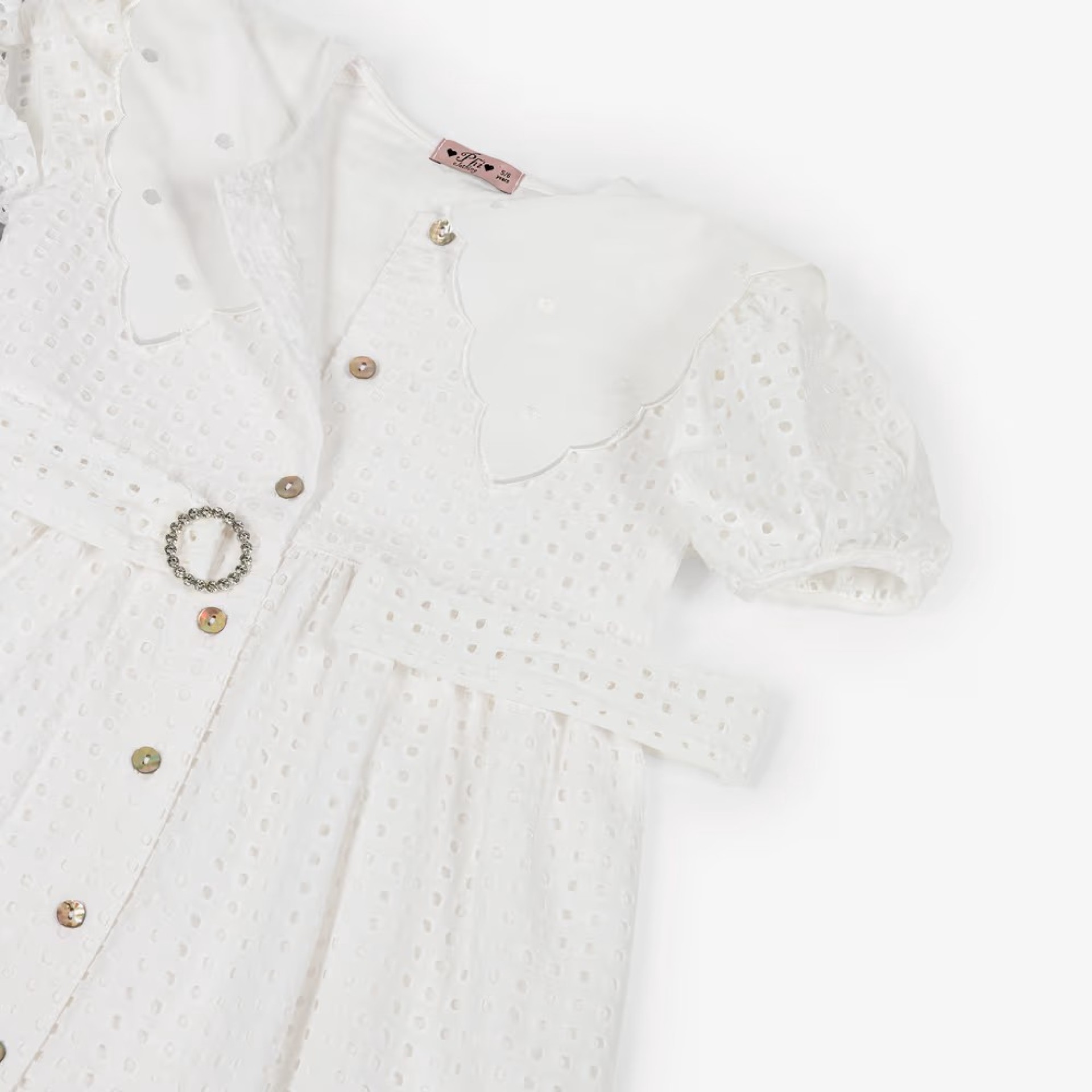 Robe blanche ornée de broderies anglaises et d'un col.