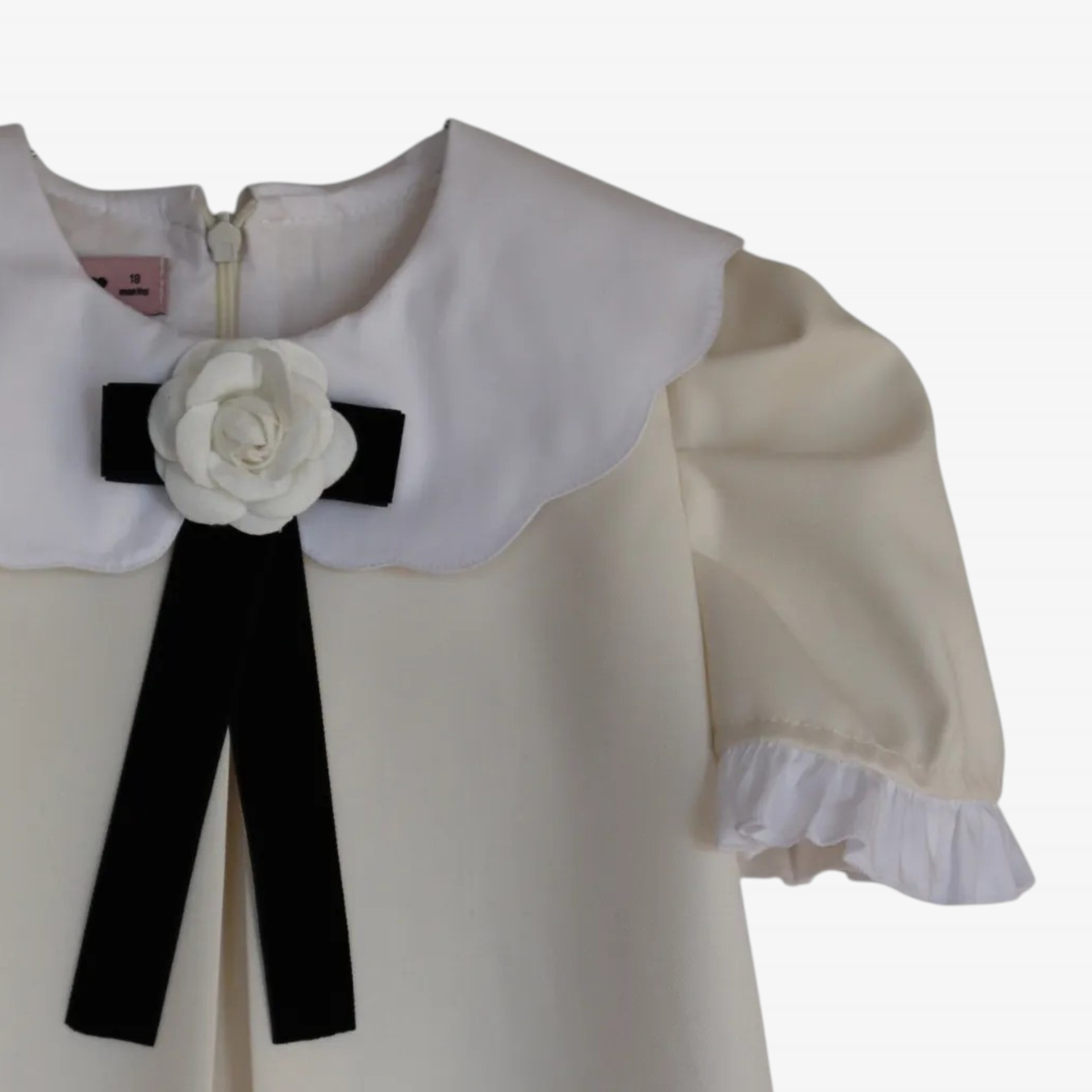 Robe blanc cassé avec nœud et fleur.